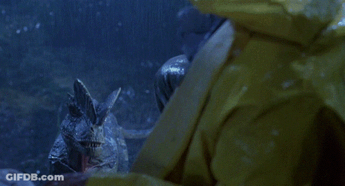 A Man In A Yellow Raincoat Is Being Attacked By A Dinosaur In Front Of A Jeep That Says Good Year GIF