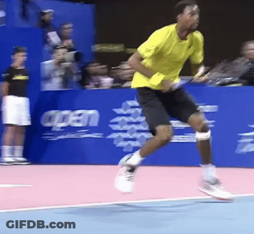 A Man In A Yellow Shirt And Black Shorts Is Jumping In The Air GIF