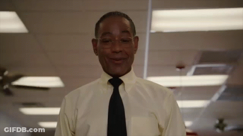 A Man In A Yellow Shirt And Black Tie Smiles GIF