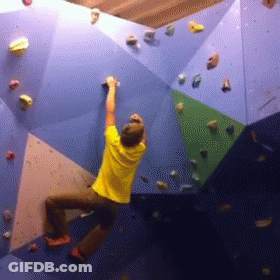 A Man In A Yellow Shirt Is Climbing Up A Climbing Wall GIF