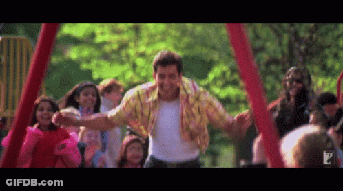 A Man In A Yellow Shirt Is Dancing In Front Of A Crowd Of Children GIF