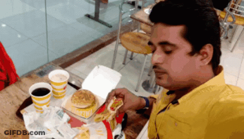 A Man In A Yellow Shirt Is Eating A Mcdonald 'S Burger GIF