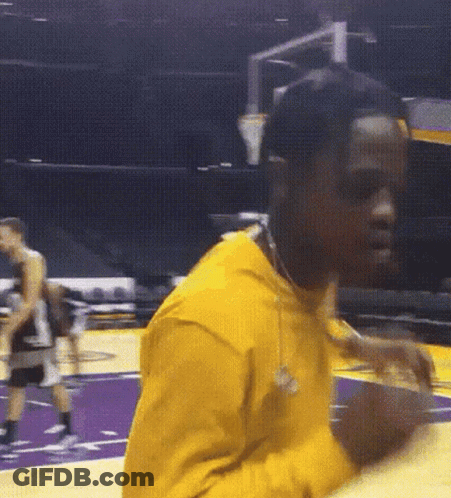 A Man In A Yellow Shirt Is Holding A Basketball On A Court GIF