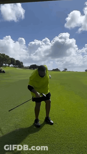 A Man In A Yellow Shirt Is Holding A Golf Club GIF