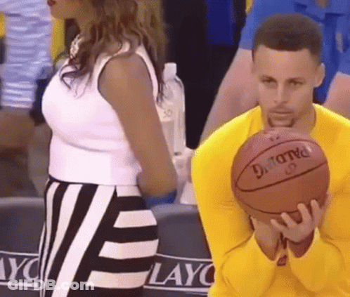 A Man In A Yellow Shirt Is Holding A Spalding Basketball While A Woman Stands Behind Him . GIF
