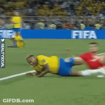 A Man In A Yellow Shirt Is Laying On The Ground On A Soccer Field In Front Of A Sign That Says Fifa GIF