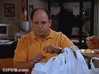 A Man In A Yellow Shirt Is Sitting At A Table With A Plastic Bag In Front Of Him GIF