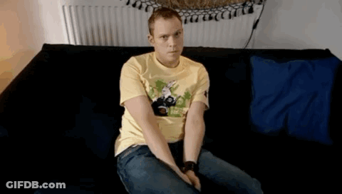 A Man In A Yellow Shirt Is Sitting On A Black Couch GIF