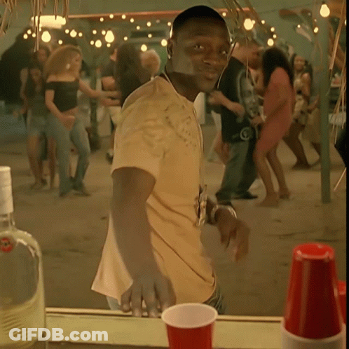 A Man In A Yellow Shirt Is Standing In Front Of A Crowd GIF
