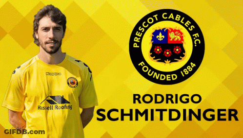 A Man In A Yellow Shirt Is Standing In Front Of A Prescot Cables Fc Logo GIF