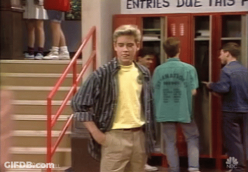 A Man In A Yellow Shirt Is Standing In Front Of A Sign That Says Entries Due This GIF