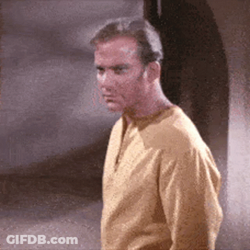 A Man In A Yellow Shirt Is Standing In Front Of A Wall GIF