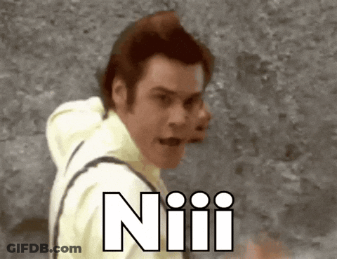 A Man In A Yellow Shirt Is Standing In Front Of A Wall With The Word Niiii Written In White GIF