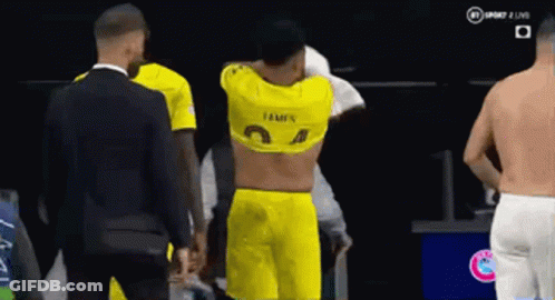 A Man In A Yellow Shirt Is Standing Next To A Man In A Suit . GIF