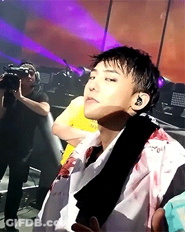 A Man In A Yellow Shirt Is Taking A Picture Of A Man In A White Shirt With Blood On His Shirt GIF