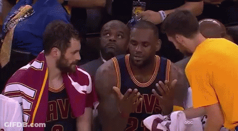 A Man In A Yellow Shirt Is Talking To A Basketball Player In A Cavs Uniform GIF