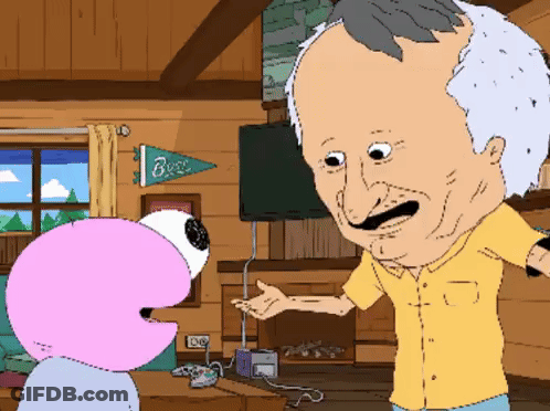 A Man In A Yellow Shirt Is Talking To A Pink Flamingo In A Living Room With A Banner That Says Buzz GIF