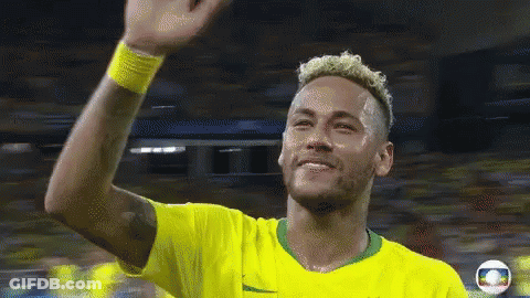 A Man In A Yellow Shirt Is Waving His Hand In The Air GIF