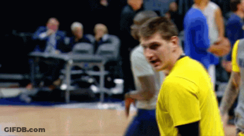 A Man In A Yellow Shirt Stands On A Basketball Court With Other Players GIF
