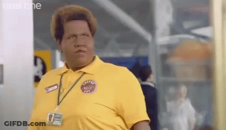 A Man In A Yellow Shirt With A Name Tag Around His Neck Is Standing In A Room . GIF