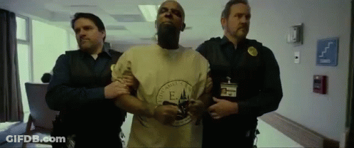 A Man In A Yellow Shirt With The Letter E On It Is Being Led By Two Men GIF