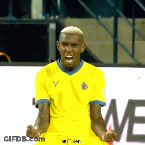 A Man In A Yellow Shirt With The Letter V On The Front GIF