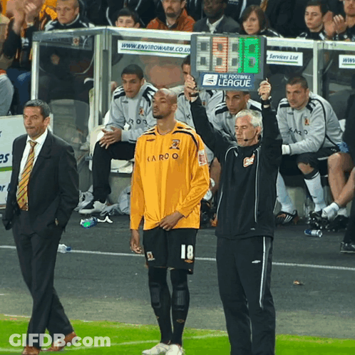 A Man In A Yellow Shirt With The Number 18 On It Stands On A Soccer Field GIF