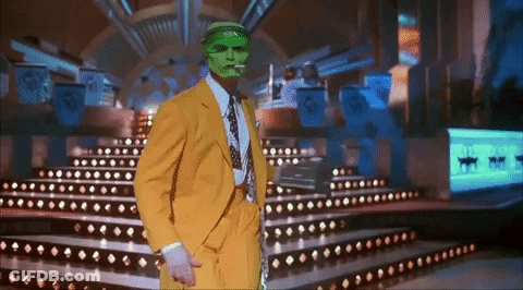 A Man In A Yellow Suit And Green Mask Is Standing On A Stage GIF