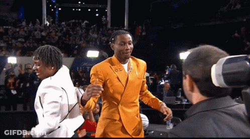A Man In A Yellow Suit Talks To A Man In A White Suit GIF