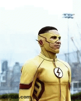 A Man In A Yellow Superhero Costume With A Lightning Bolt Emblem On His Chest GIF