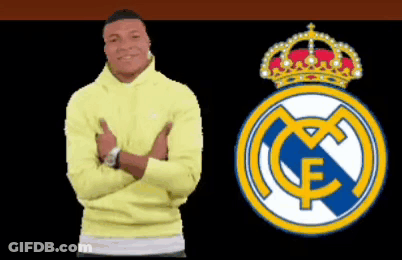 A Man In A Yellow Sweatshirt Stands Next To A Real Madrid Logo GIF