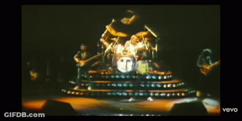 A Man In A Yellow Tank Top Is Playing Drums In A Video That Says Vevo On The Bottom Right GIF