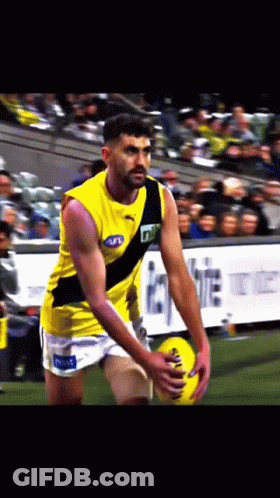 A Man In A Yellow Tank Top With A Black Stripe That Says Tnt GIF