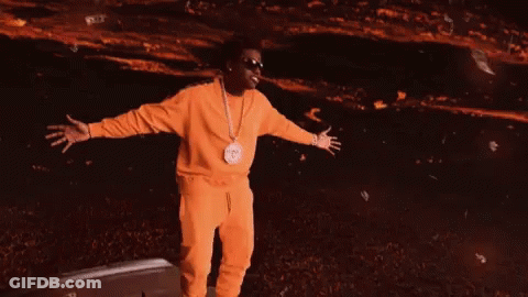 A Man In A Yellow Tracksuit Is Standing In Front Of A Green Background GIF