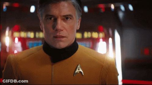 A Man In A Yellow Uniform With A Star Trek Badge GIF