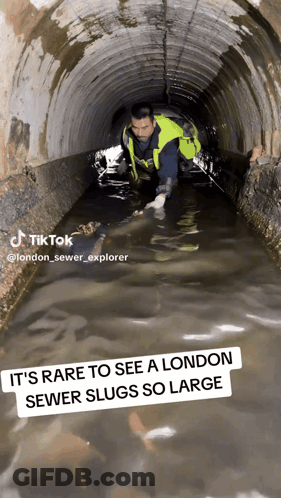 A Man In A Yellow Vest Is Crawling Through A Sewer GIF