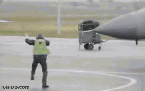 Man In Yellow Vest Next To Fighter Jet GIF