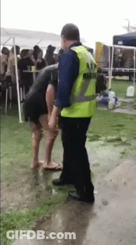 A Man In A Yellow Vest Is Standing Next To A Woman In A Black Dress . GIF