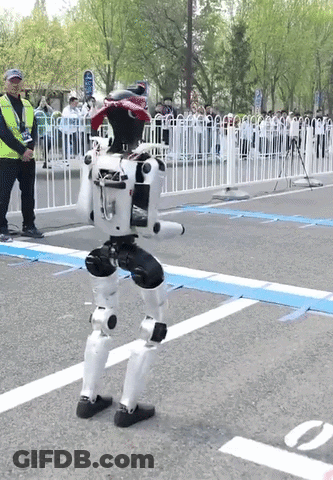 A Man In A Yellow Vest Stands Next To A Robot On The Street GIF