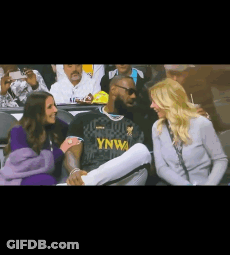A Man In A Ynwa Jersey Sits In The Stands With Two Women GIF
