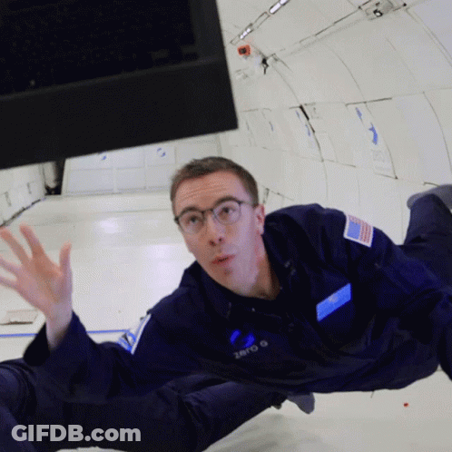 A Man In A Zero G Space Suit Is Floating In The Air GIF