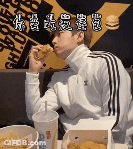 A Man In An Adidas Jacket Is Eating A Hamburger GIF