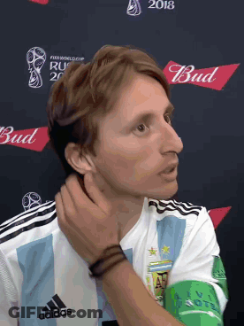 A Man In An Adidas Shirt Is Standing In Front Of A Bud Logo GIF