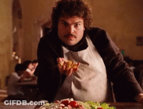 A Man In An Apron Is Holding A Piece Of Pizza In His Hand GIF