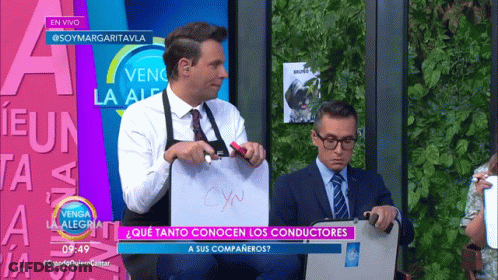 A Man In An Apron Is Holding A White Board That Says Cyn On It GIF