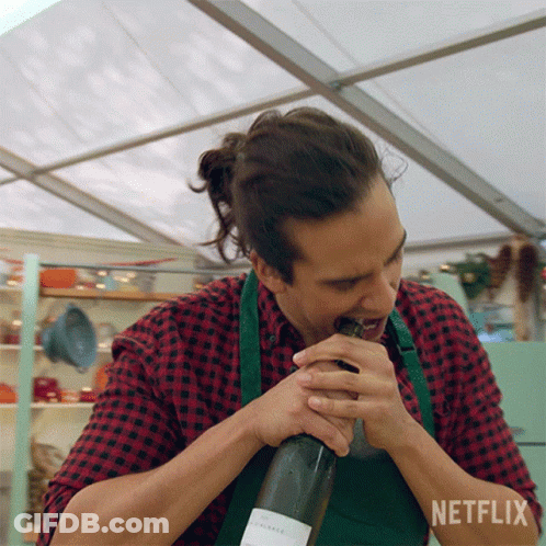 A Man In An Apron Is Opening A Bottle Of Wine With Netflix Written In The Corner GIF