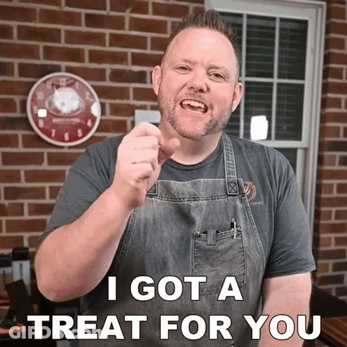 A Man In An Apron Is Pointing At The Camera With The Words I Got A Treat For You Below Him GIF