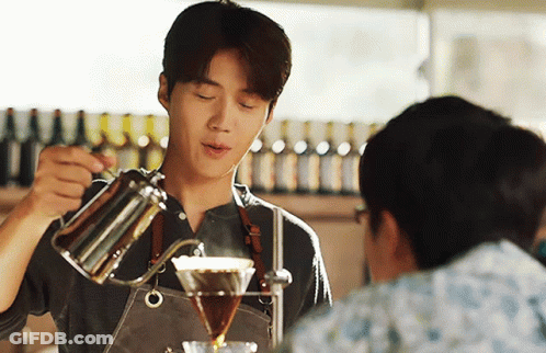 A Man In An Apron Pours Coffee Into A Glass GIF