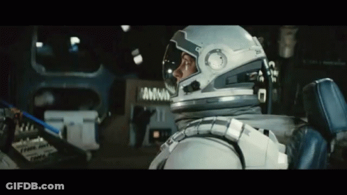 A Man In An Astronaut 'S Helmet Is Sitting In A Car GIF