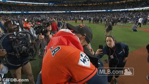 A Man In An Astros Jersey Is Hugging Another Man On A Baseball Field GIF